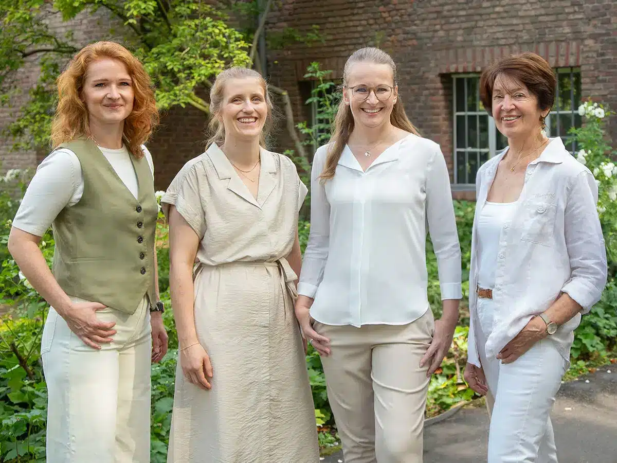 Gruppe von Frauen in weißen Leinenoutfits posiert im Freien